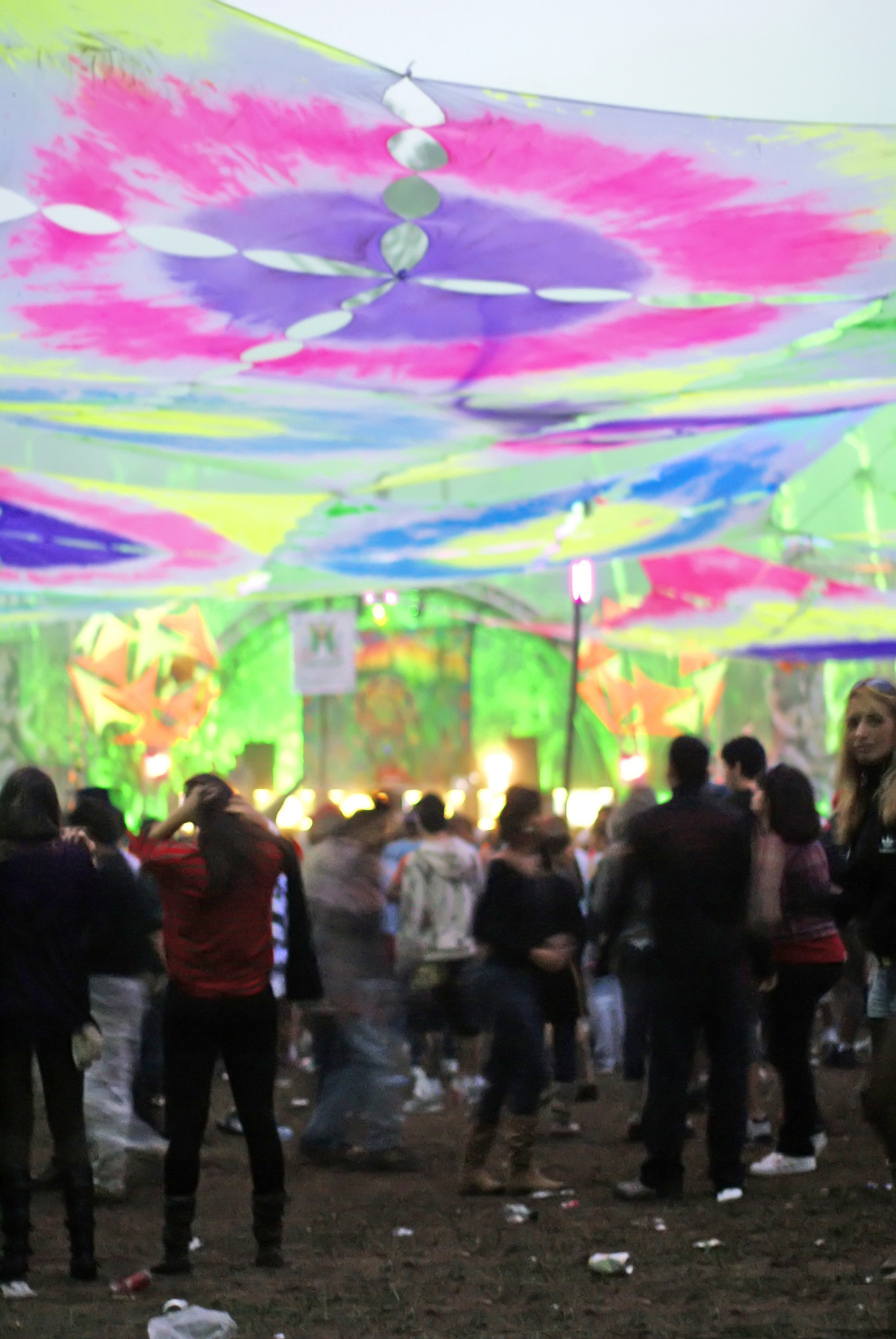Outdoor rave crowd under psychedelic canopy lights